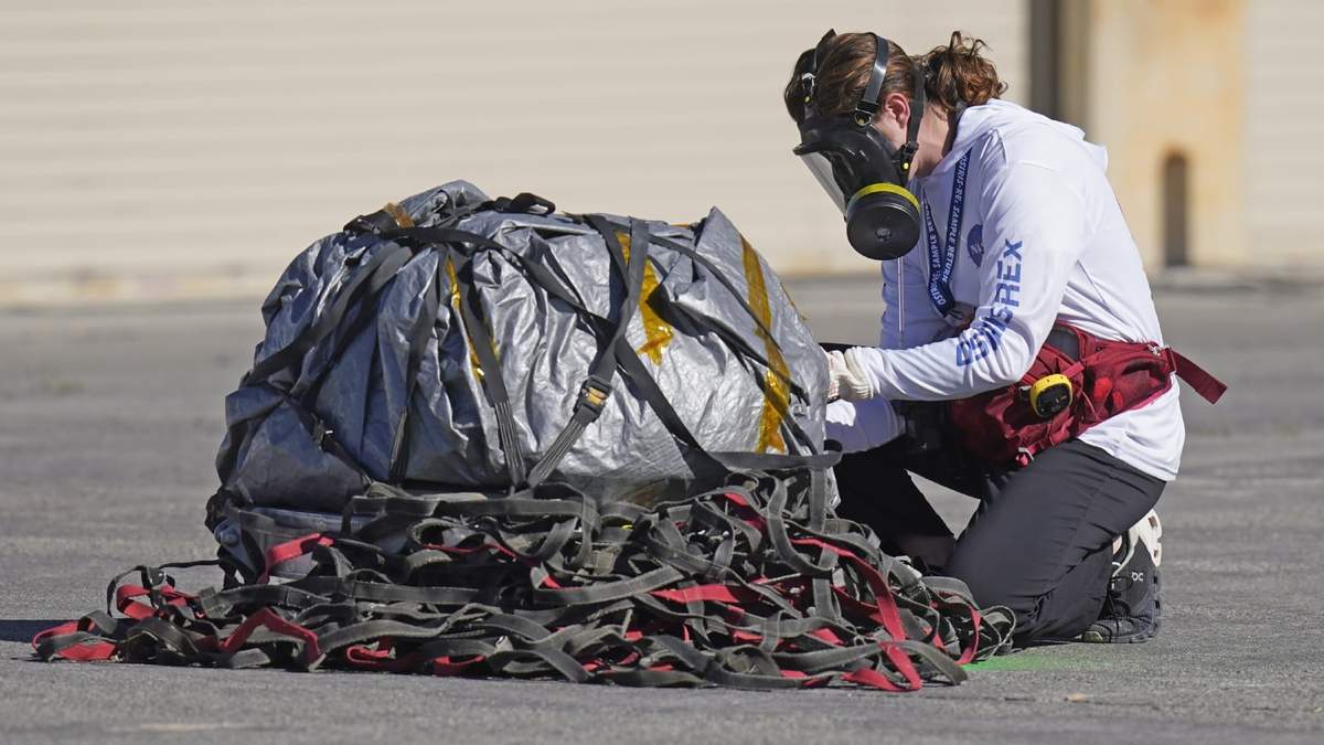 Una integrante del equipo de recuperación examina una cápsula que contiene las primeras muestras de un asteroide recolectadas por la NASA antes de ser trasladadas a una sala especial para su análisis