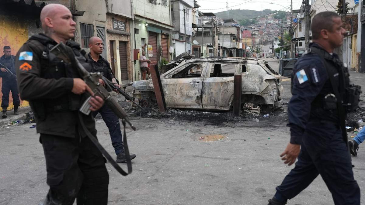 Policías pasan junto a un coche quemado que fue utilizado como barricada durante una operación policial contra presuntos narcotraficantes en la favela Complexo do Alemao, donde opera la organización criminal "Comando Vermelho", en Río de Janeiro, el 8 de octubre de 2025