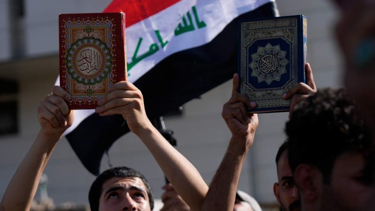Simpatizantes del sacerdote chií Muqtada al-Sadr levantan el Corán, el libro sagrado para los musulmanes, durante una manifestación frente a la embajada sueca, el 30 de junio de 2023, en Bagdad, en respuesta a la quema del Corán en Suecia