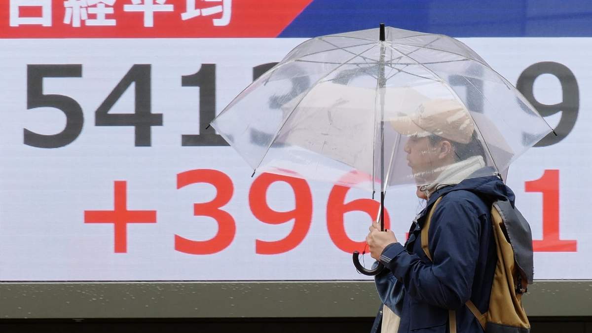 Unas personas caminan frente a un panel electrónico que muestra las cotizaciones del índice Nikkei de Japón, el jueves 2 de abril de 2026, en Tokio