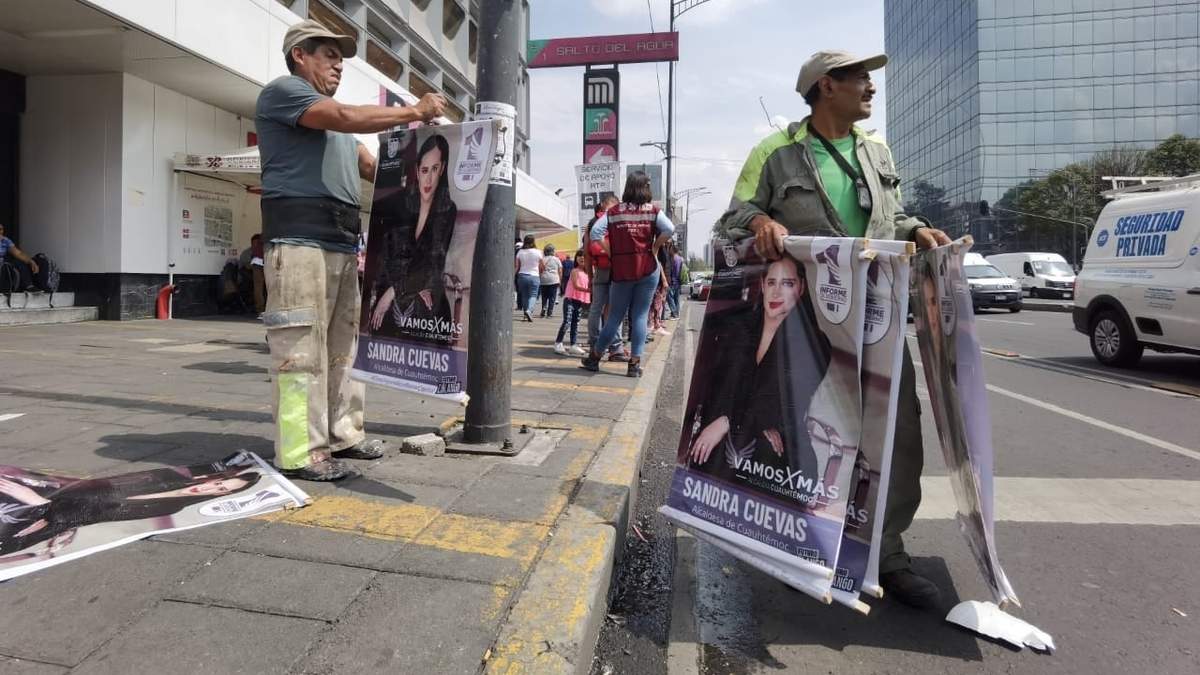 Trabajadores colocan pendones con la imagen de la alcaldesa afuera de la estación Salto del Agua del Metro