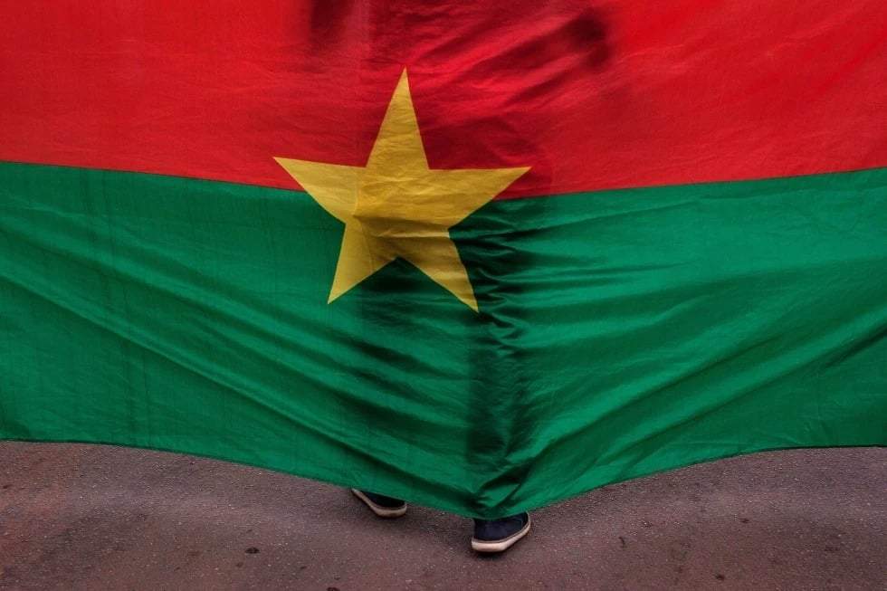 La bandera de Burkina Faso con un hombre de pie frente a ella, durante una ceremonia conmemorativa en Uagadugú, Burkina Faso, el 23 de enero de 2016.
