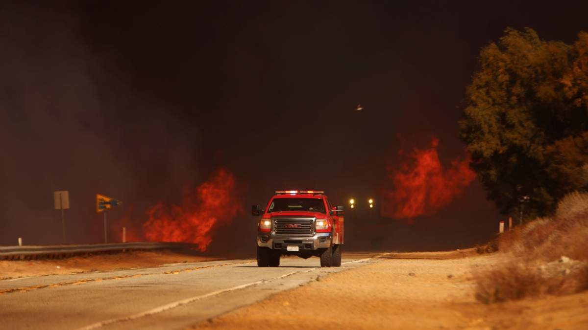 Una camioneta de bomberos pasa junto a las llamas provocadas por el incendio Hughes, en Castaic, California, este miércoles