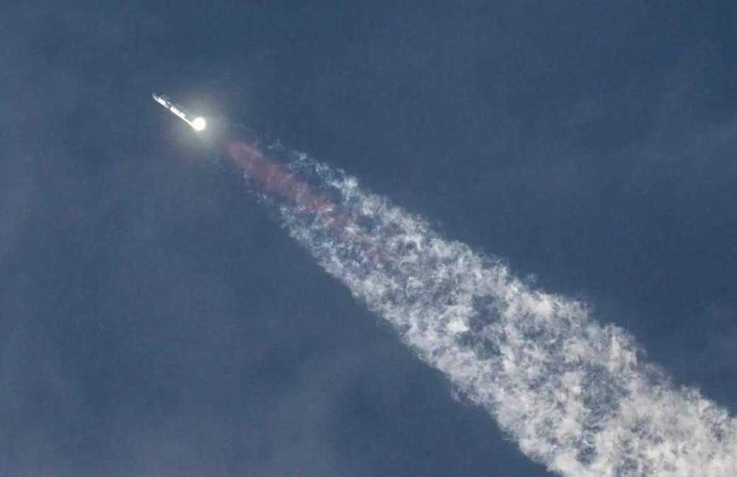 Un grupo de personas observa a la distancia la preparación del megacohete de SpaceX para su despegue desde Starbase en Boca Chica, Texas