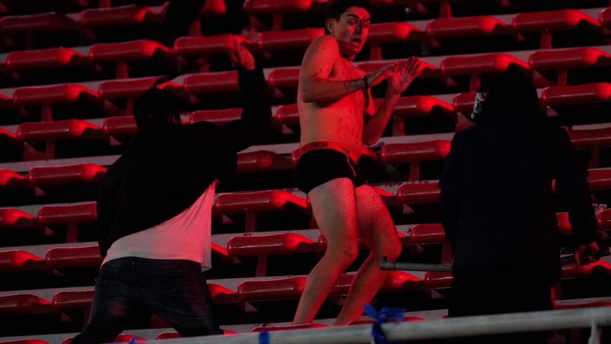 Un hincha de la Universidad de Chile es golpeado por fanáticos del Independiente de Argentina durante el partido de vuelta de los octavos de final de la Copa Sudamericana en el estadio Libertadores de América en Avellaneda, Argentina