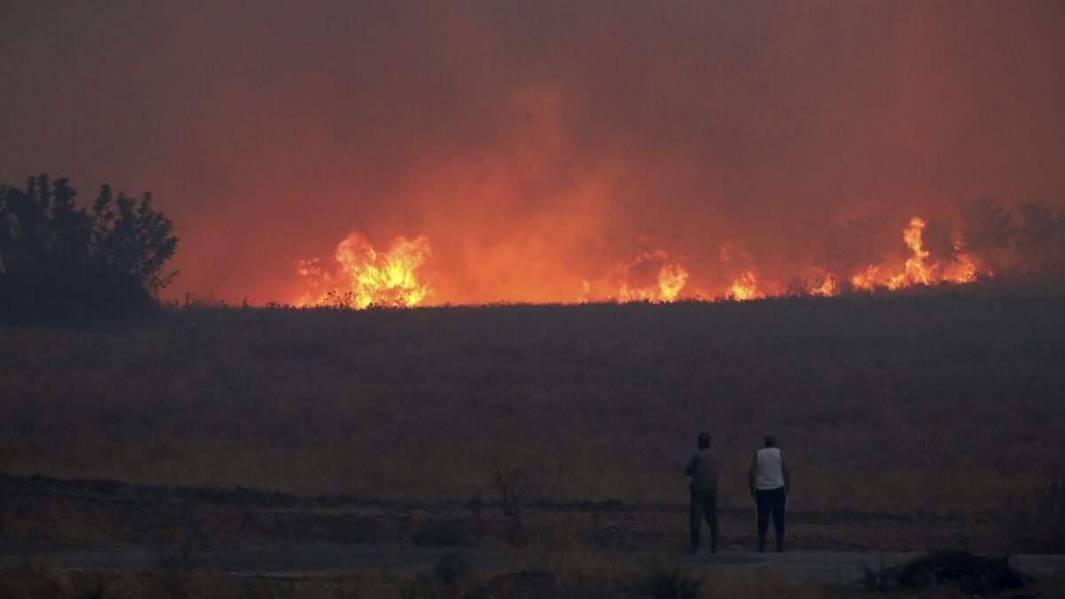 Gente observa un incendio forestal cerca de la ciudad nororiental de Alejandrópolis, Grecia