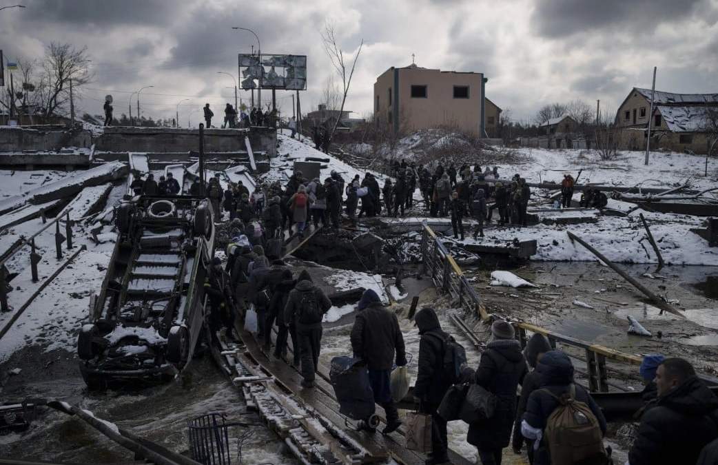 cranianos cruzan un puente improvisado bajo un puente roto mientras huyen de Irpin, a las afueras de Kiev, Ucrania, el martes 8 de marzo de 2022.