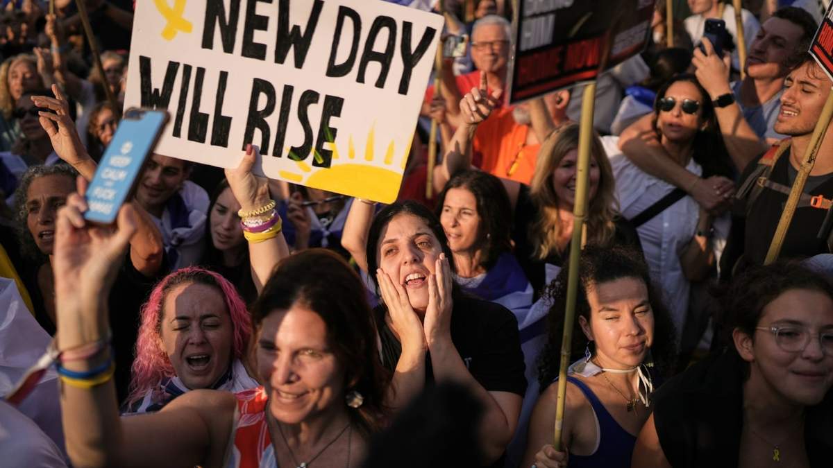 Gente reacciona mientras se reúne para ver una retransmisión en vivo de la liberación de rehenes de Gaza en lo que se conoce como la Plaza de los Rehenes en Tel Aviv, Israel, el lunes 13 de octubre de 2025