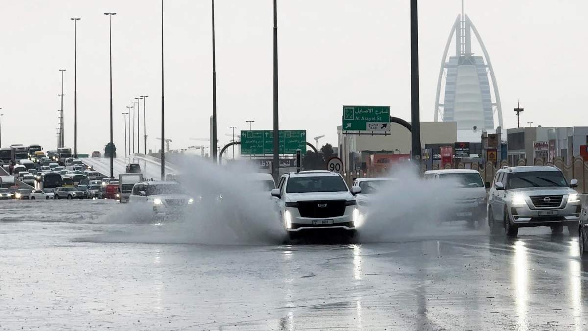 Una camioneta arroja agua a su paso por una carretera anegada, con el edificio Burj Al Arab, de fondo, en Dubái