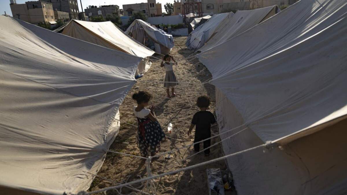 Niños palestinos desplazados por los bombardeos israelíes sobre Gaza caminan entre tiendas proporcionadas por la ONU en un campamento levantado en Khan Younis