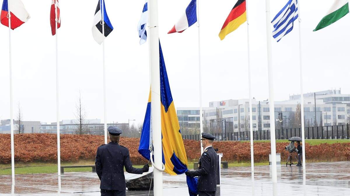 Dos militares se preparan para izar la bandera de Suecia en una ceremonia para conmemorar la entrada del país en la OTAN, en la sede de la OTAN