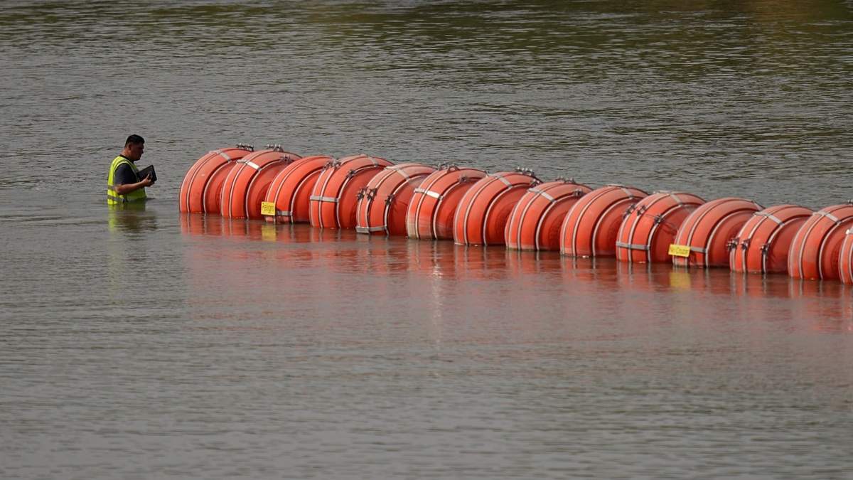 Un trabajador inspecciona las boyas utilizadas como barrera a lo largo del río Bravo