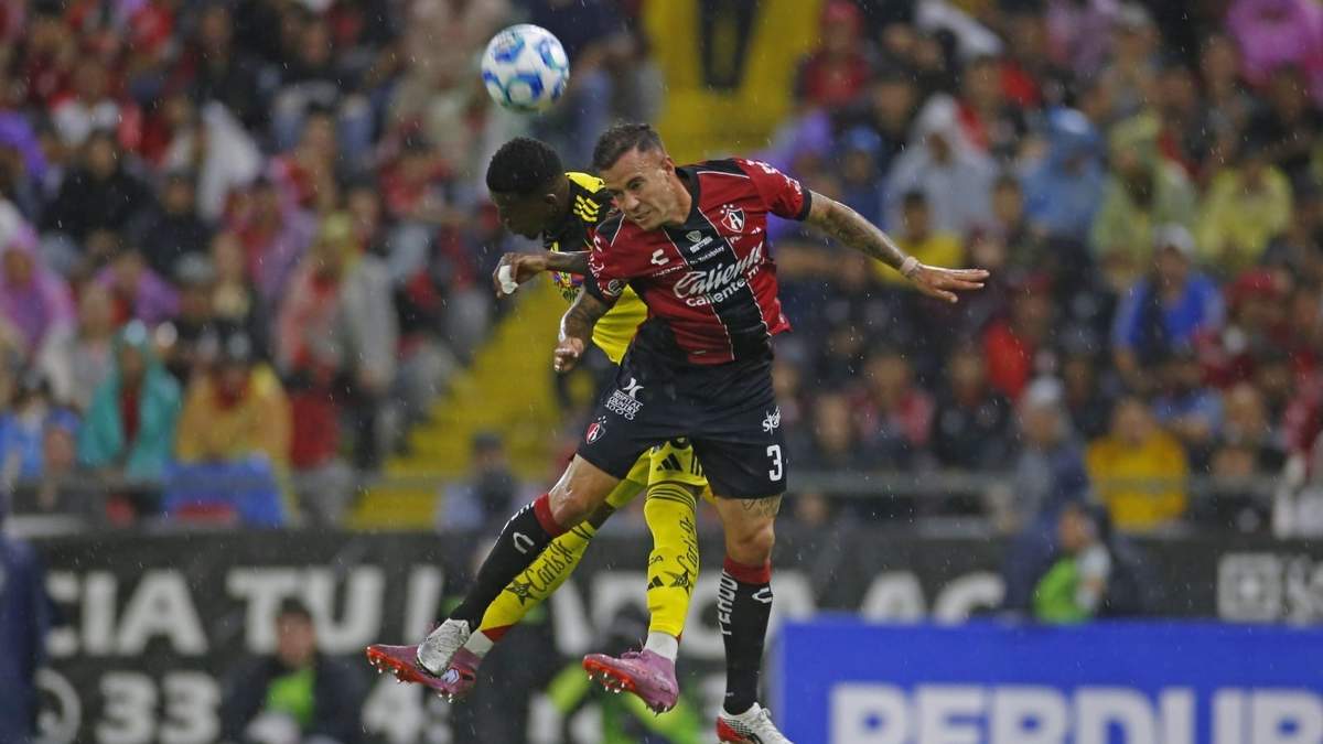 Gustavo Ferrareis, jugador de Atlas, disputa el balón con el contrario de América, Cristian Borja