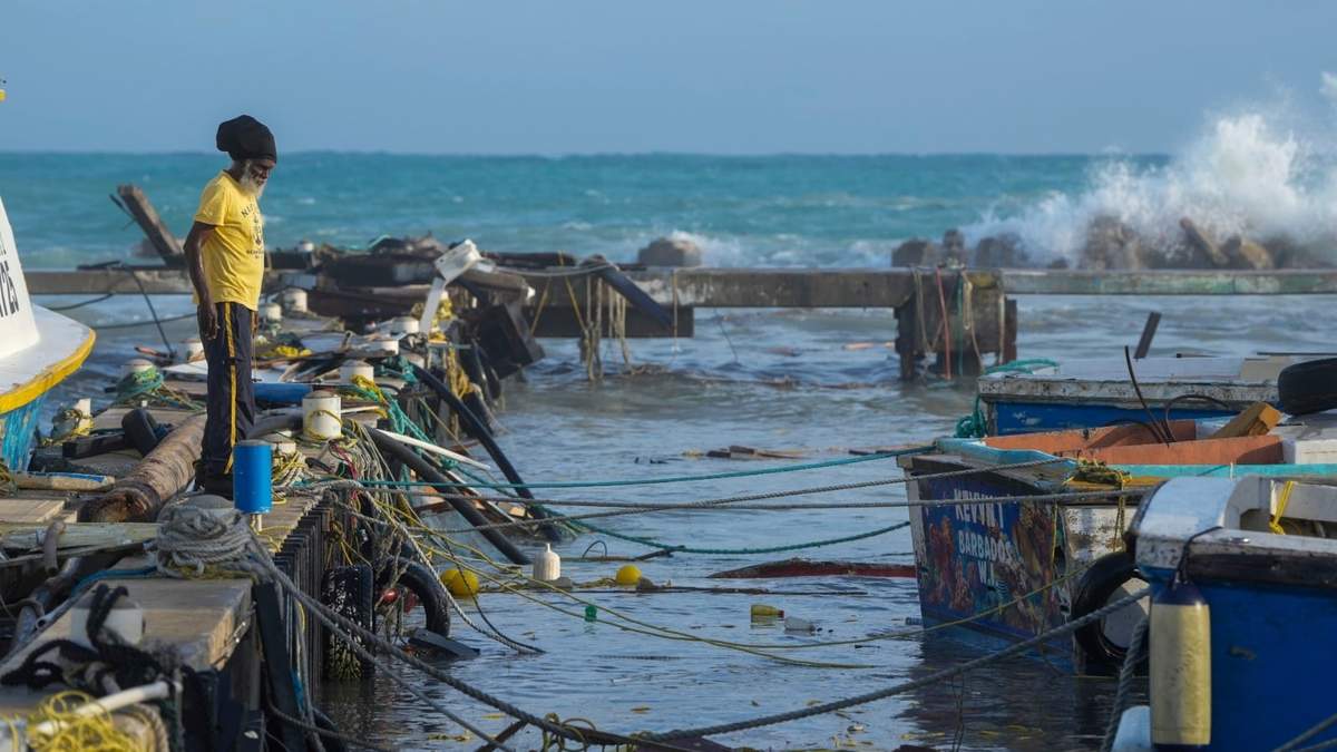 Un pescador observa los barcos dañados por el huracán Beryl en Bridgetown Fisheries en Barbados