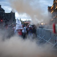 Encapuchados chocan con policías, lanzan vallas y queman una bandera tras marcha del 12 de octubre