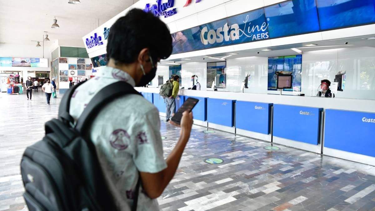 Un joven con cubrebocas usa su celular en México.