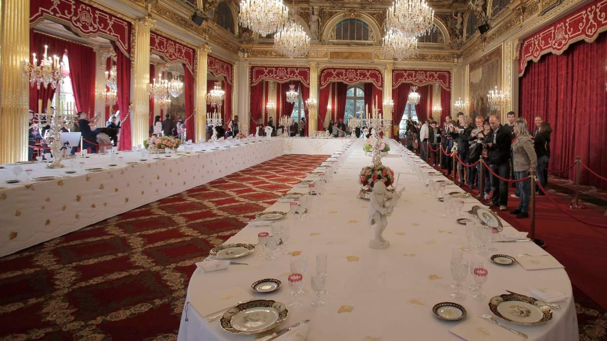 Visitantes miran una mesa puesta con platos y copas para cenas oficiales en el Palacio del Elíseo en París, el sábado 5 de septiembre de 2012
