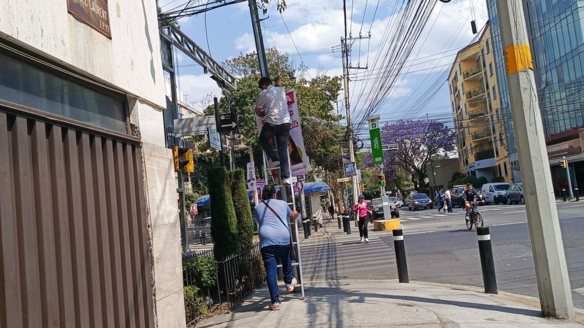 Dos hombres retiran publicidad de Santiago Taboada para colocar la de Clara Brugada
