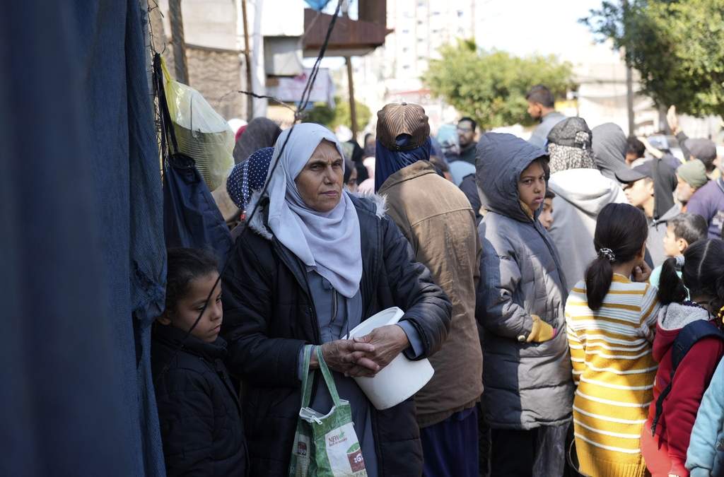 Palestinos hacen fila para recibir alimentos, en Deir al-Balah, en la Franja de Gaza, 14 de febrero de 2025