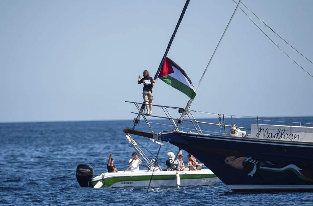 La activista climática Greta Thunberg se ve junto a una bandera palestina en el velero Madleen antes de zarpar a Gaza junto con activistas de la Flotilla de la Libertad, en el puerto siciliano de Catania, Italia, el domingo 1 de junio de 2025