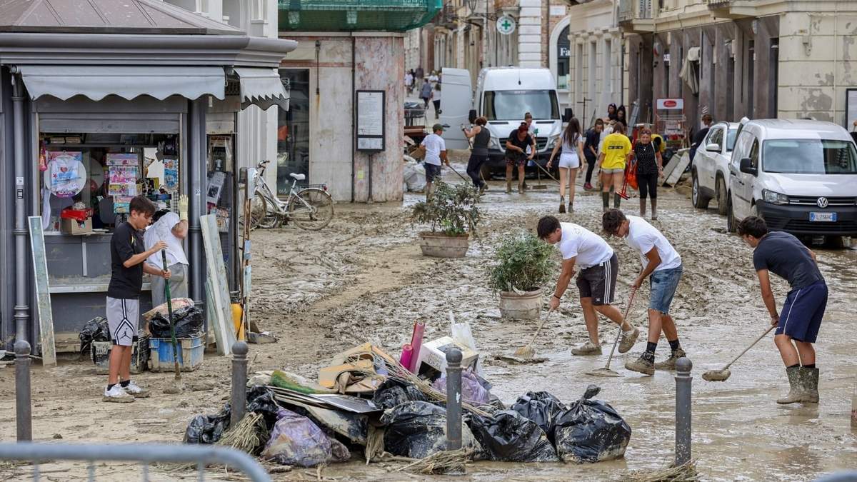 Personas remueven lodo de una calle de Senigallia, en el centro de Italia