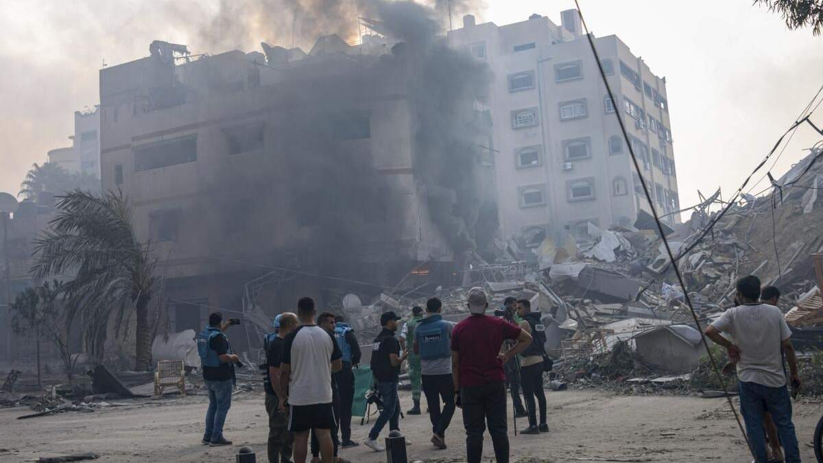En esta imagen de archivo, reporteros observan mientras palestinos inspeccionan un edificio alcanzado por un bombardeo israelí en la Ciudad de Gaza, 8 de octubre de 2023. El limitado número de periodistas que están en Gaza tratan de informar sobre la guerra con Israel mientras sufren los mismos problemas que la asediada población palestina de la Franja