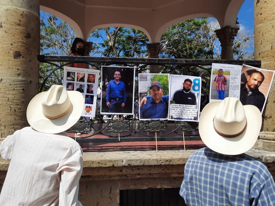 Hombres miran cárteles de búsqueda en Teocaltiche