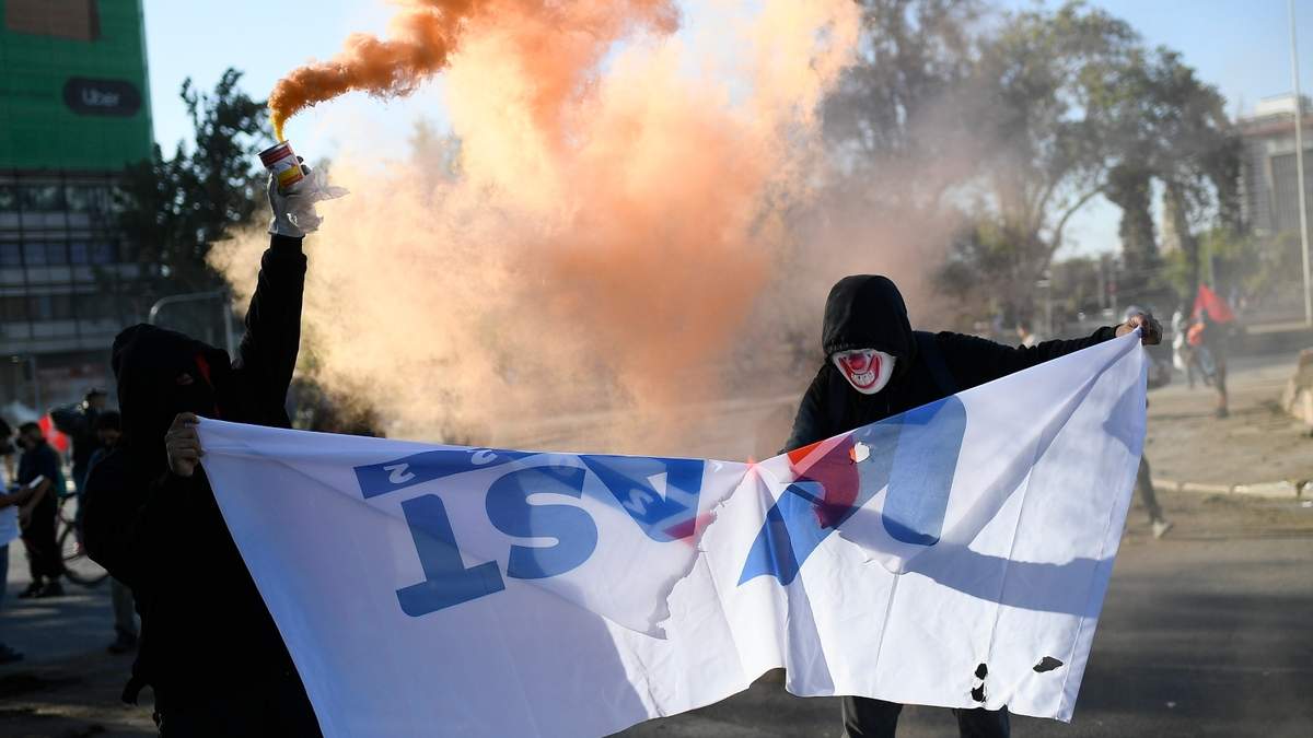 Manifestantes queman una bandera de campaña electoral del candidato presidencial José Antonio Kast