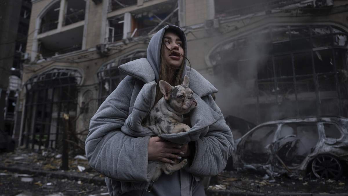 Ivanna, calienta a su perro frente a un coche en llamas destruido tras un reciente ataque ruso en Kiev, Ucrania, viernes 20 de diciembre de 2024. ()