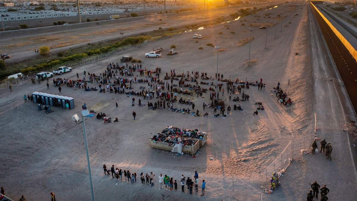 Migrantes aguardan afuera de una puerta en la cerca fronteriza el jueves 11 de mayo de 2023 para ingresar a El Paso, Texas
