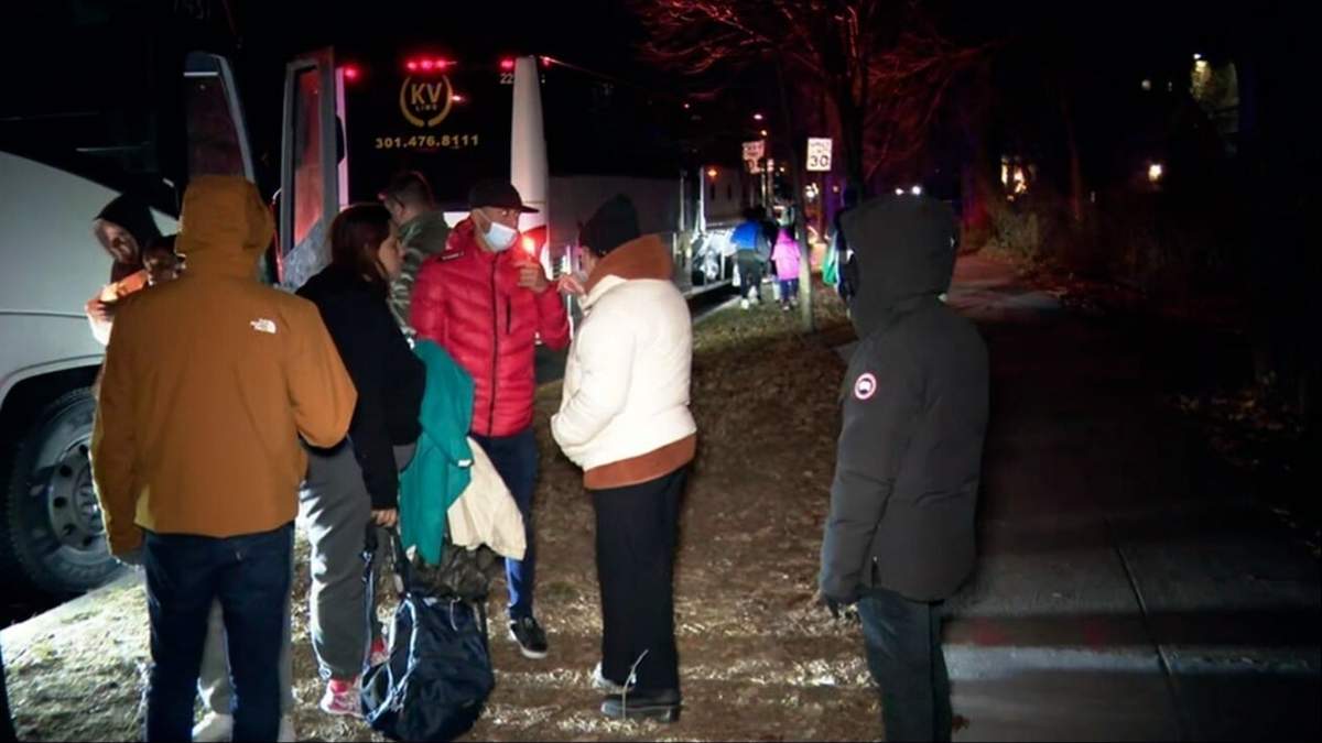 Fotografía proporcionada por la organización WJLA que muestra a familias de migrantes subiendo a un autobús para transportarlos desde los alrededores de la residencia de la vicepresidenta Kamala Harris a una iglesia