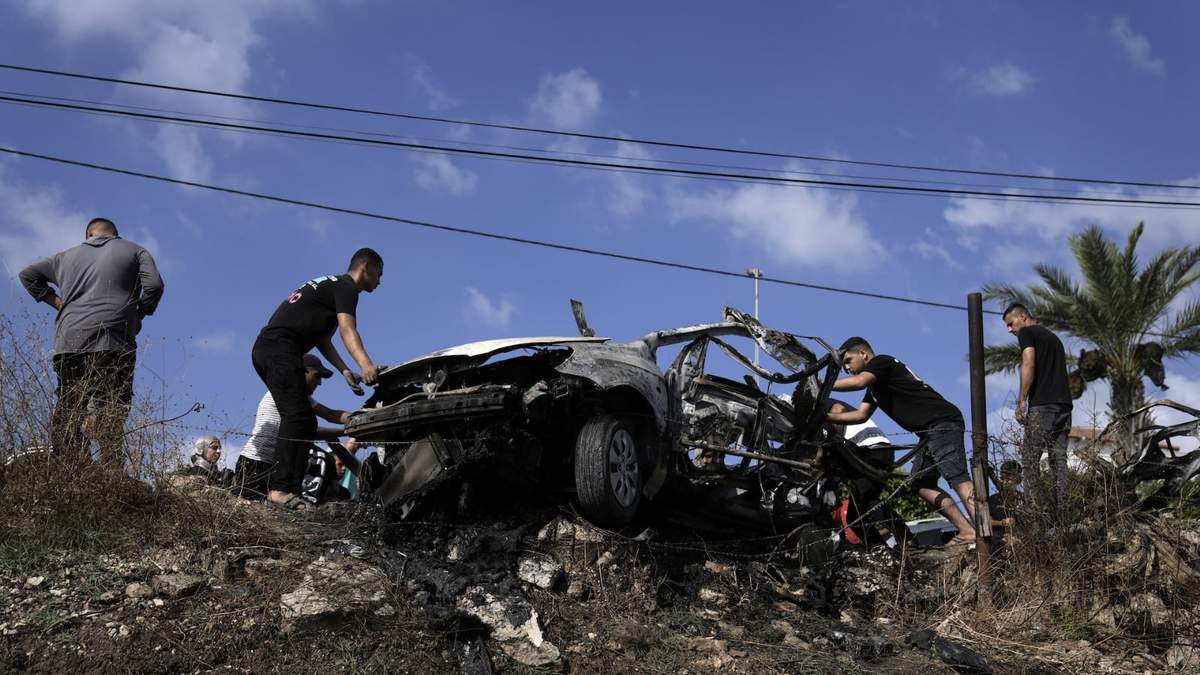 Palestinos se acercan a un auto destruido por el ataque de un dron en la localidad de Zeita, al norte de la ciudad cisjordana de Tulkarem