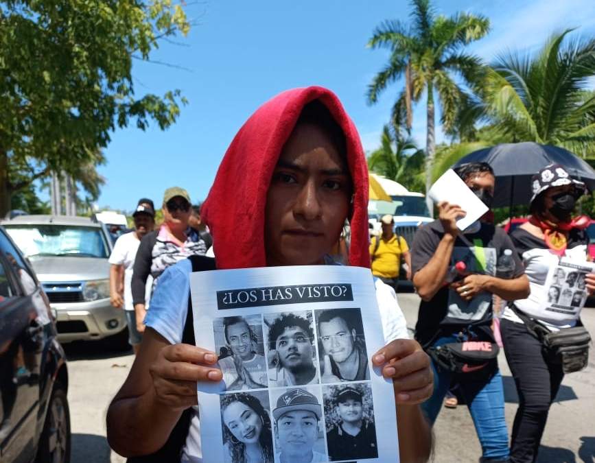 Una mujer sostiene una impresión con la imagen de los seis jóvenes desaparecidos el 1 de septiembre en Acapulco