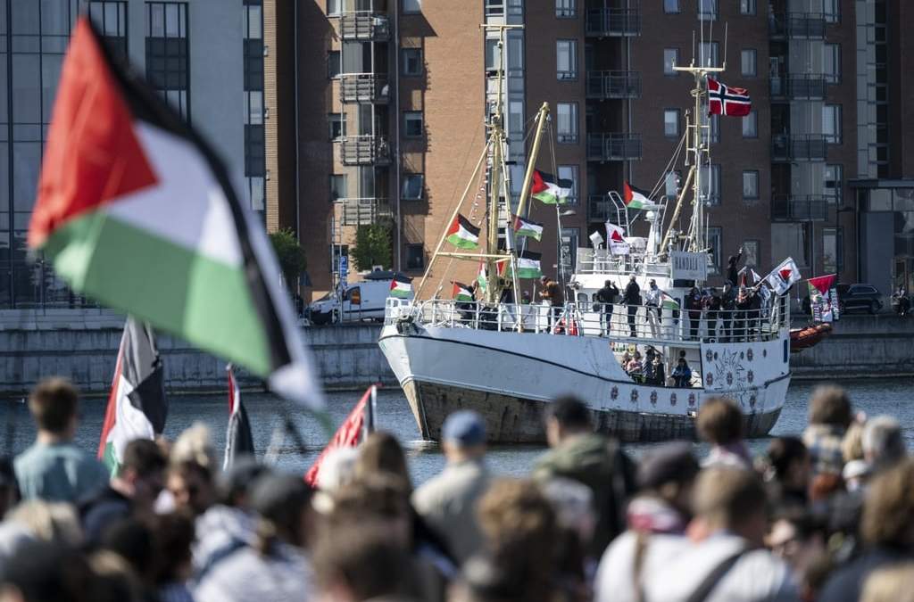 ARCHIVO - Manifestantes con banderas palestinas miran mientras el barco con destino a Gaza "Handala" llega al puerto de Malmö, Suecia, el miércoles 8 de mayo de 2024
