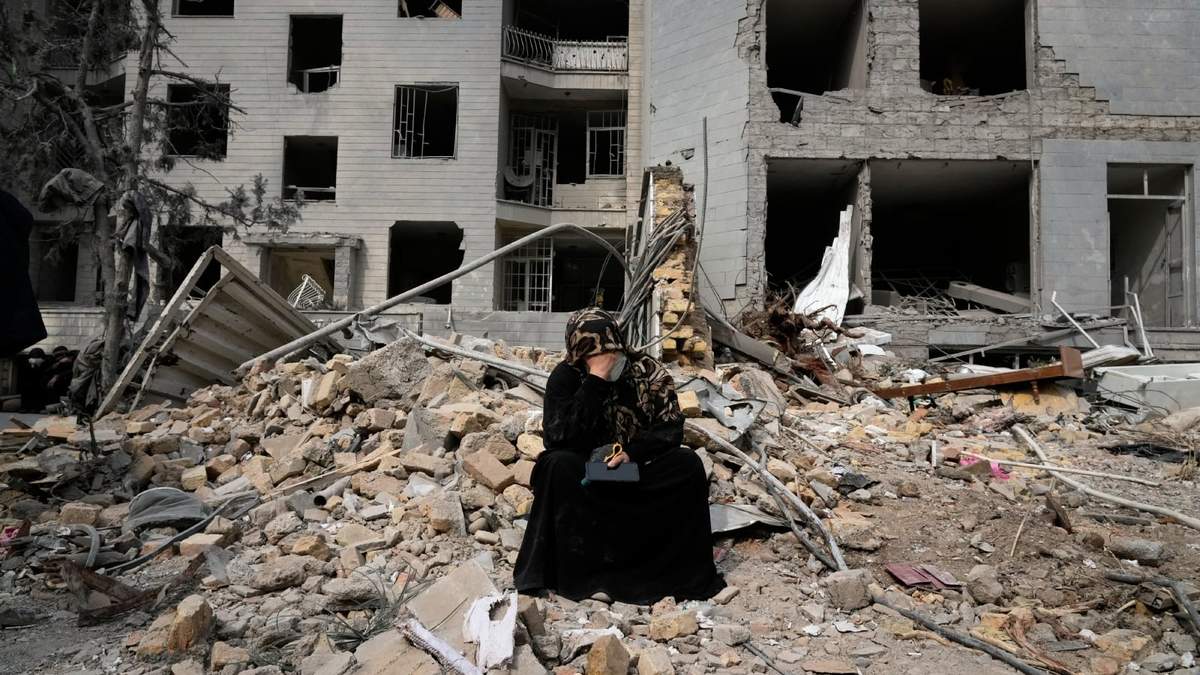 Una mujer se sienta entre escombros ante un edificio residencia dañado el lunes pasado en una campaña aérea de Israel y Estados Unidos en Teherán, Irán, el jueves 12 de marzo de 2026