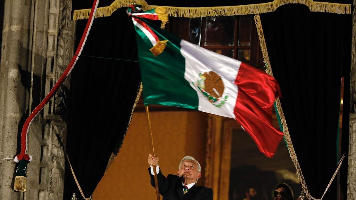 El presidente López Obrador ondea la bandera tras dar el Grito