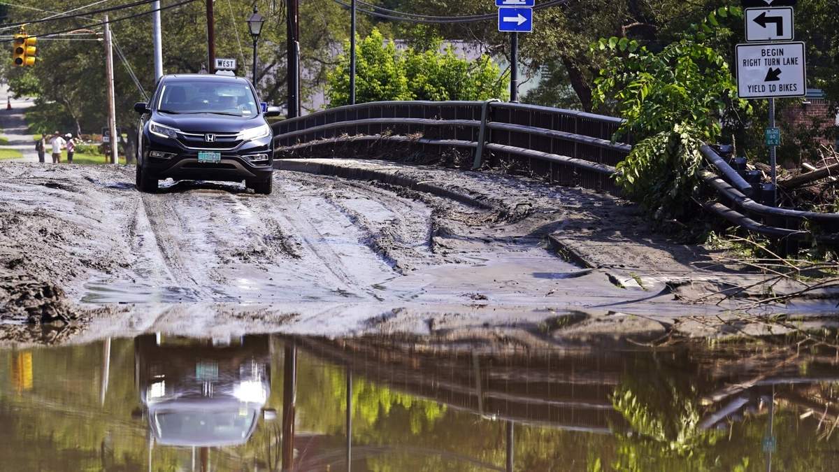 ARCHIVO - Un conductor se detiene en un puente cubierto de lodo mientras decide si atravesar una zona inundada en el río Winooski, el 12 de julio de 2023 en Montpelier, Vermont