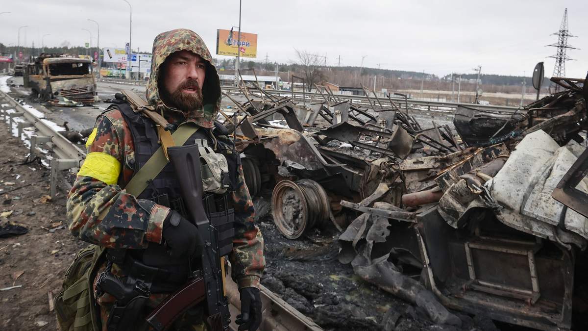 Un combatiente ucraniano contempla los restos de un vehículo militar ruso en las cercanías de Kiev, Ucrania.