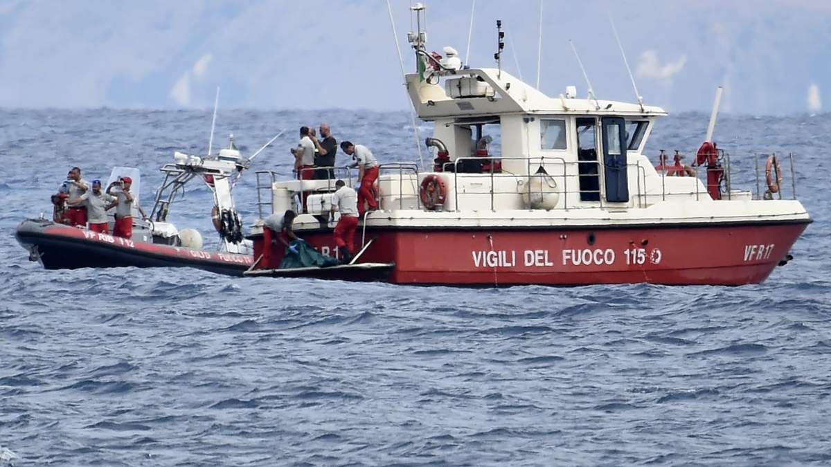 Buzos de los bomberos italianos llevan hasta un barco la bolsa con los restos mortales de una de las víctimas del naufragio del yate Bayesian, el 21 de agosto de 2024, en Porticello, cerca de Palermo, en el sur de Italia