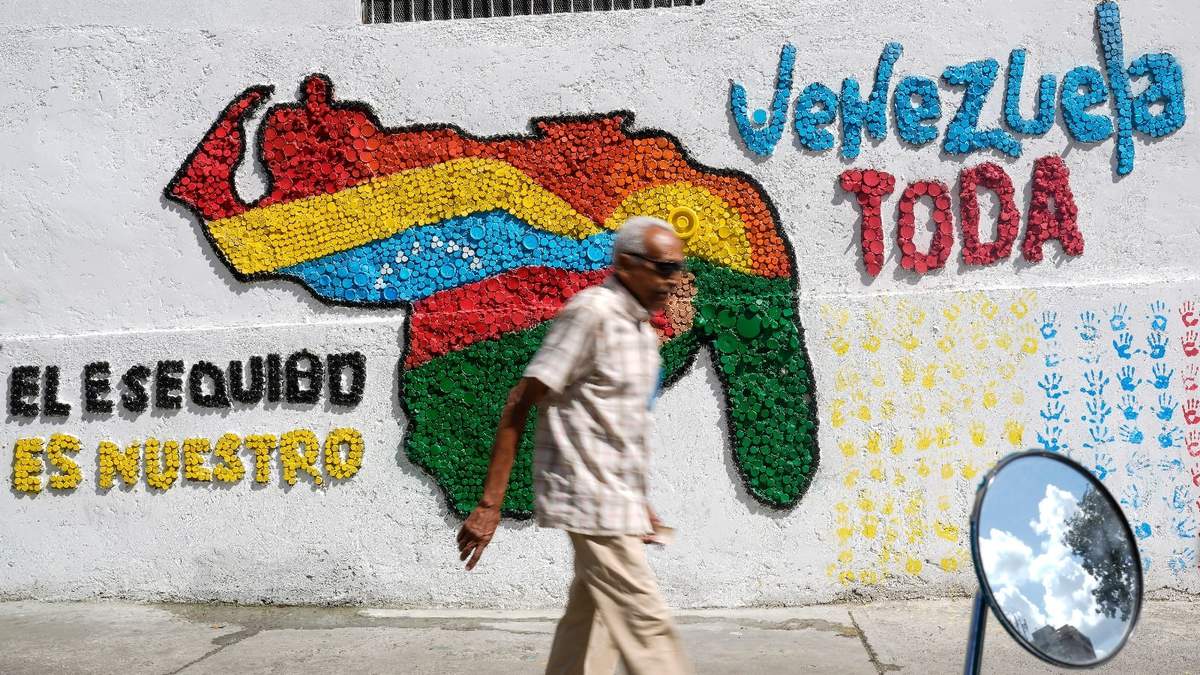 Un hombre camina en Caracas frente a un mural de un mapa de Venezuela con el territorio de Esequibo incluido