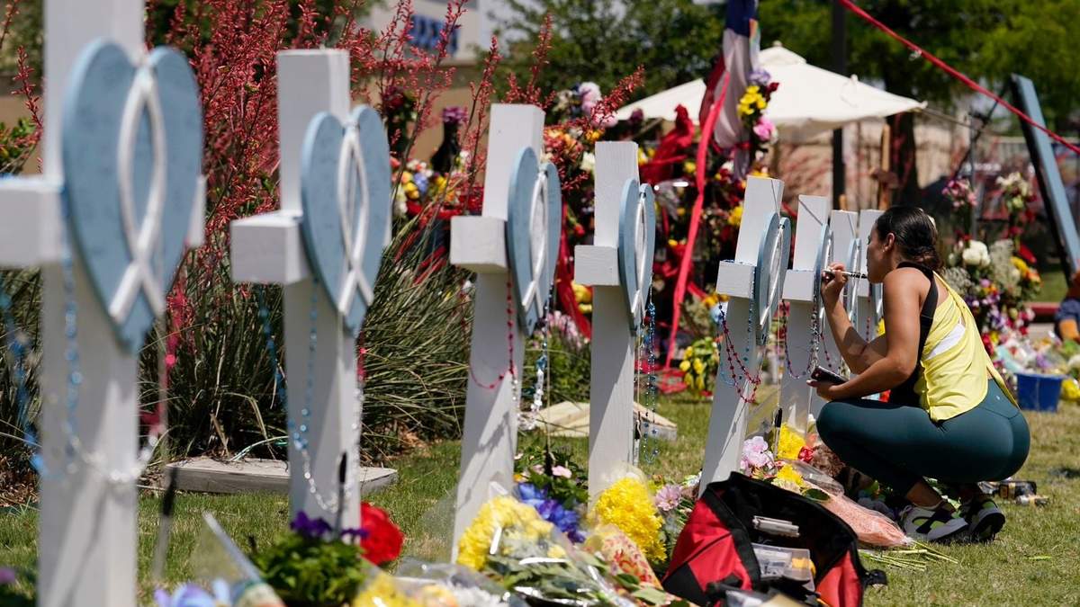 Una mujer firma una cruz alineada junto a otras en un altar improvisado en honor de las víctimas de la masacre en Allen, Texas