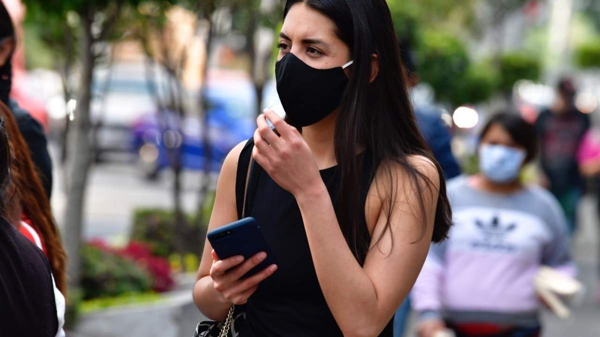 Una chica camina por la calle con su celular en la mano
