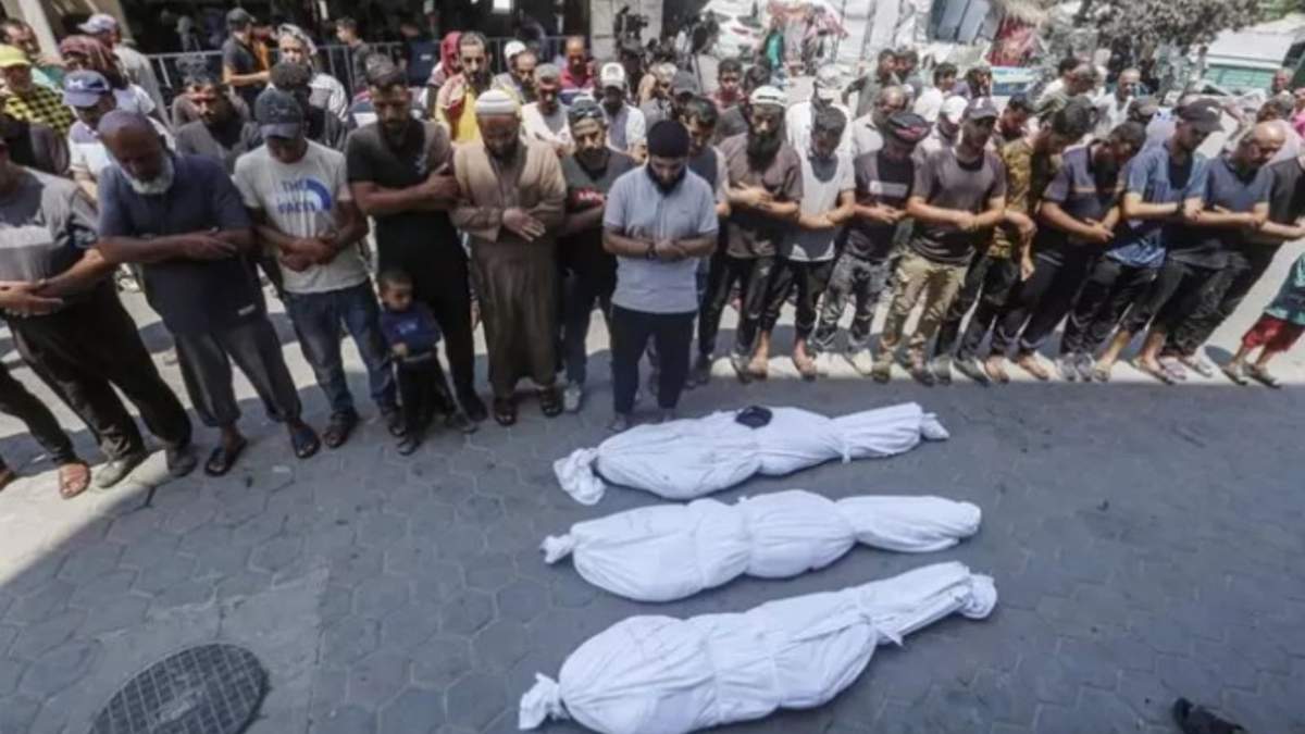 Un grupo de personas reza a los muertos dejados por un nuevo ataque de Israel sobre la Franja de Gaza