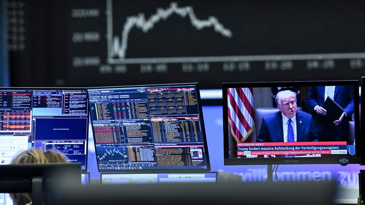 Tras una pantalla que muestra al presidente de Estados Unidos, Donald Trump, la pantalla con el índice bursátil Dax muestra un precio a la baja de las acciones en Fráncfort, Alemania, el jueves 3 de abril de 2025, después de Trump presentara un paquete de aranceles que llevó las bolsas a pérdidas