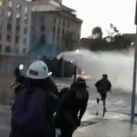 Chilenos se enfrentan a policías en Santiago; los disipan con tanquetas de agua