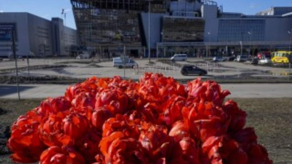 Un ramo de flores colocado en la cerca frente a la sala de conciertos incendiada Crocus City Hall en las afueras de Moscú, 27 de marzo de 2024