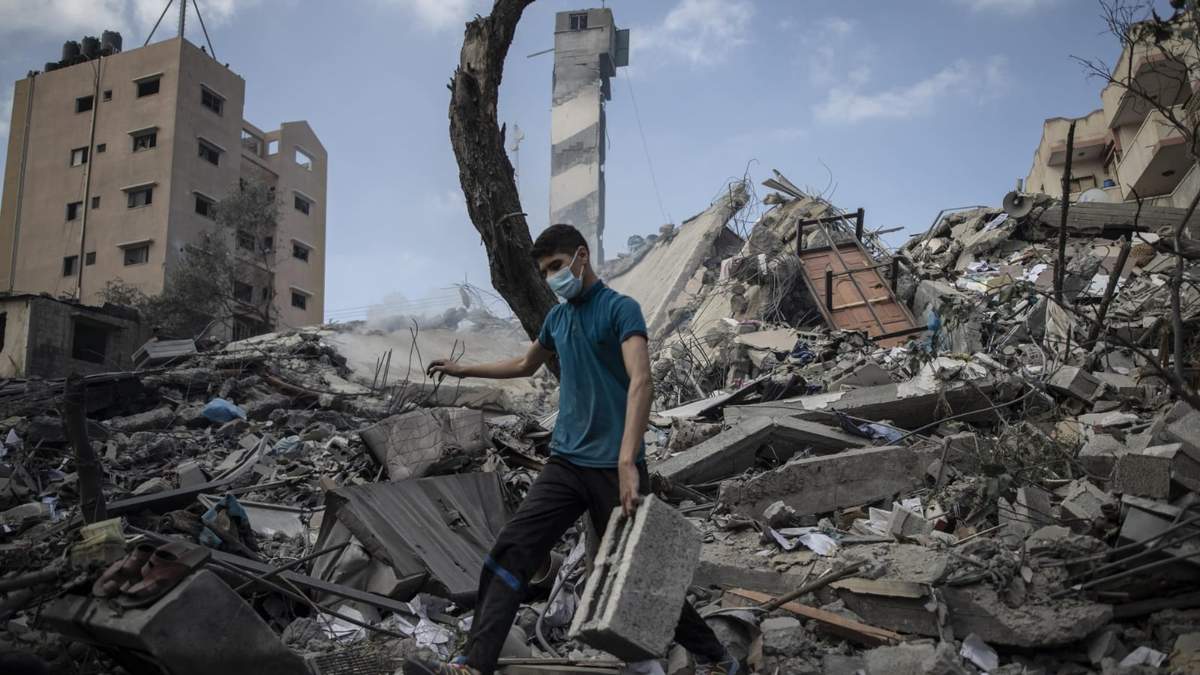 Un joven camina sobre los escombros de un edificio en la Franja de Gaza, Palestina. Fuente: (Twitter)