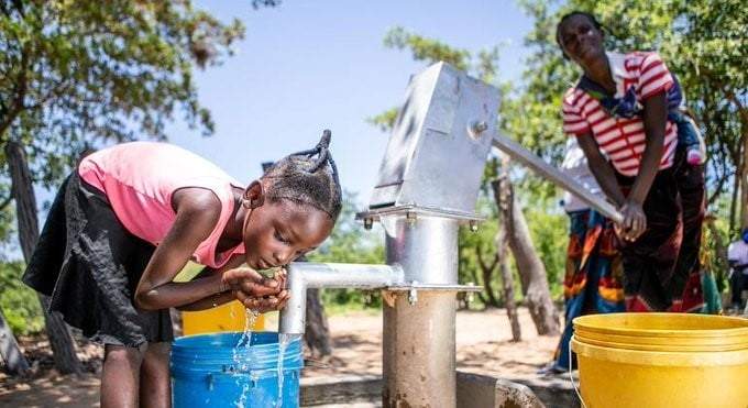 Una niña bebe agua extraída de una toma recién rehabilitada en Zambia