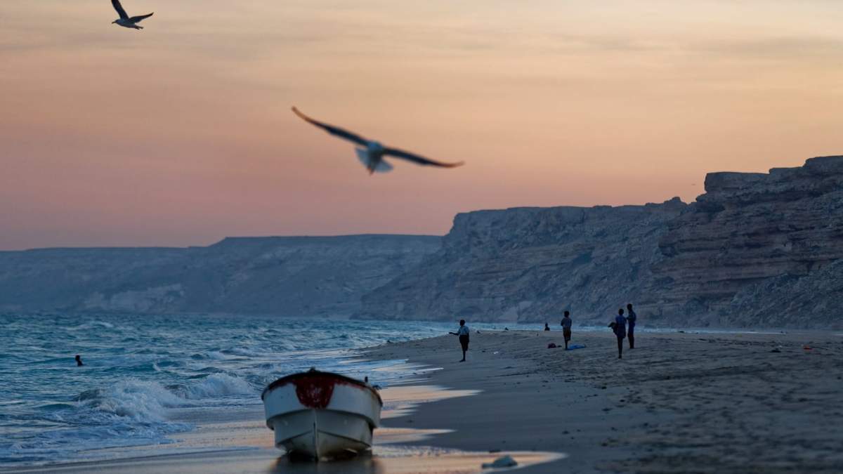 Pescadores miran al océano Índico al atardecer en una playa en la antigua localidad pirata de Eyl, en la región semiautónoma nororiental de Puntlandia, Somalia