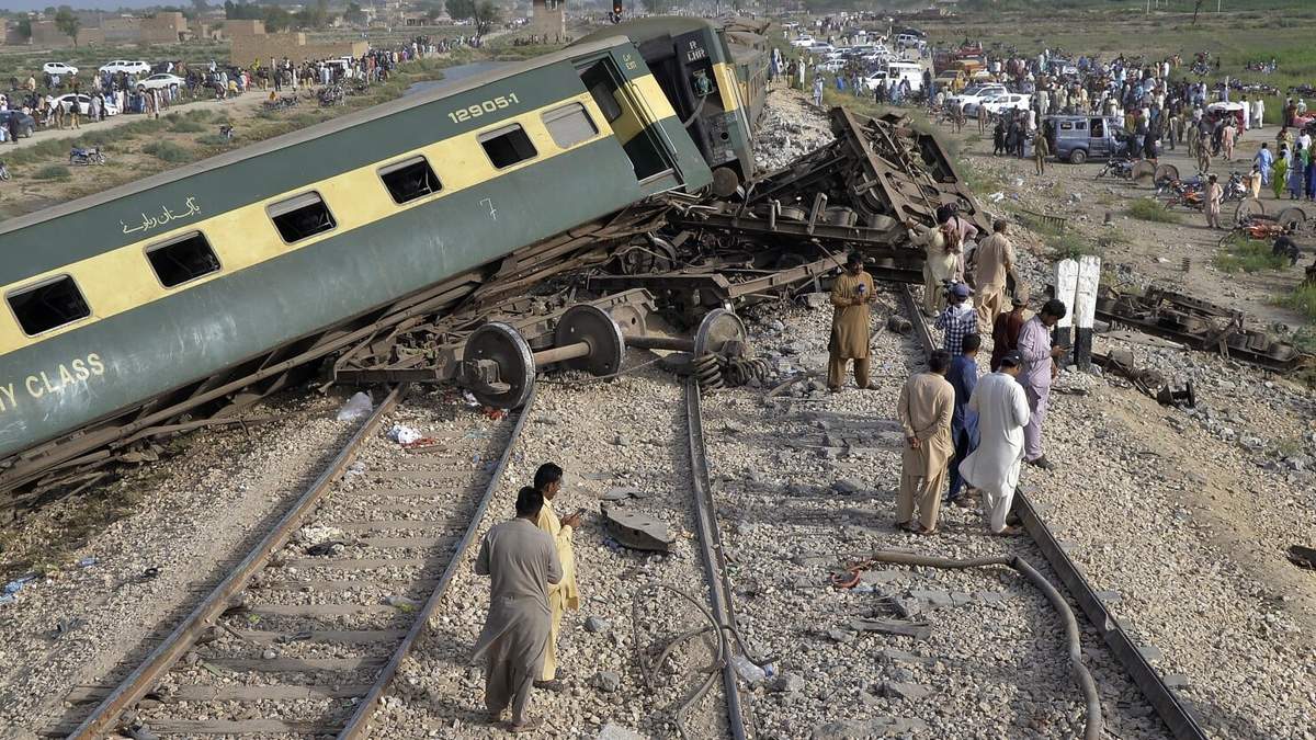 Civiles observan los vagones dañados de u tren de pasajeros que se descarriló cerca de Nawabshah, Pakistán